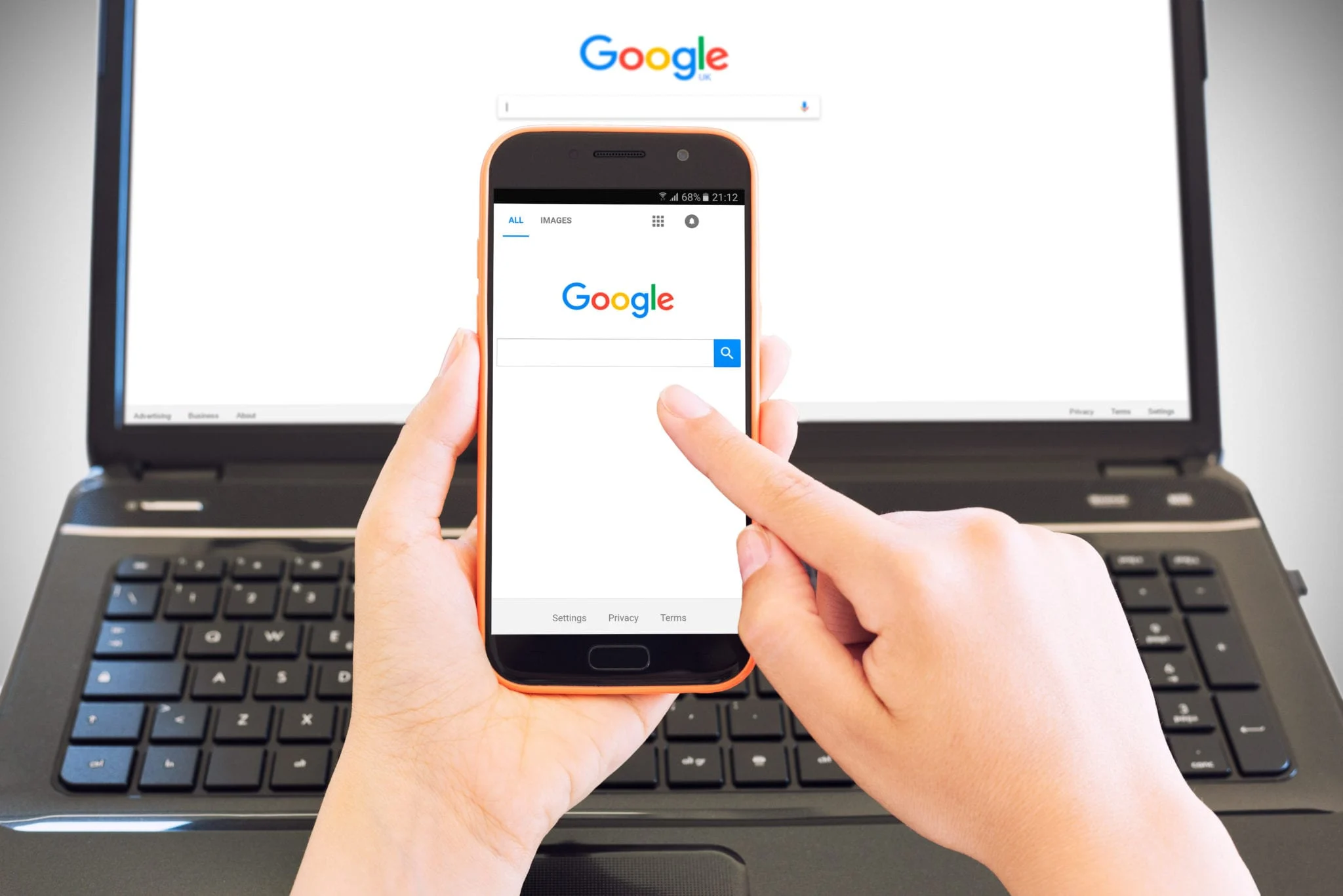 cagliari italy 30 05 2017 smartphone on female hands browsing google home page and in background a portable computer with the same site this is an illustrative editorial image